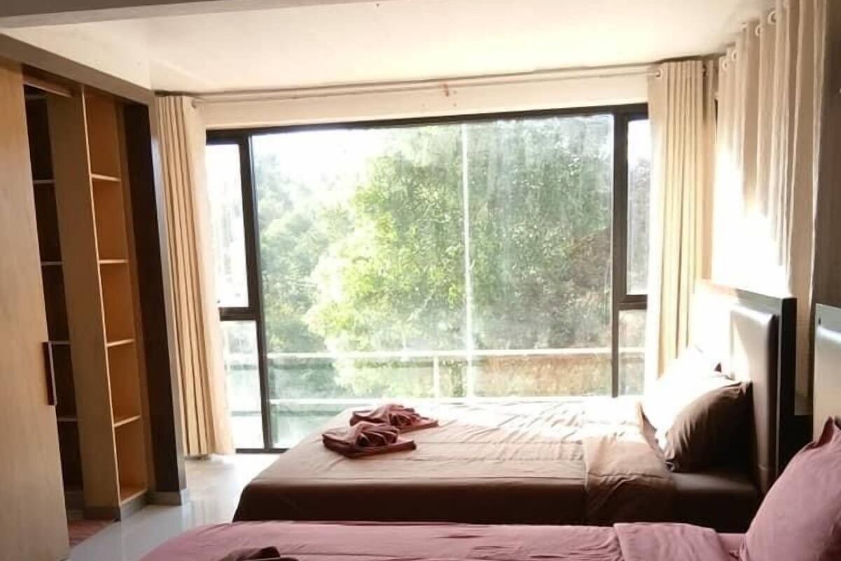 Une chambre d’hôtel avec deux lits, une grande fenêtre et une armoire.