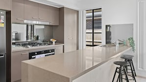 Una cocina moderna con una isla central, electrodomésticos de acero inoxidable y vistas a un balcón.