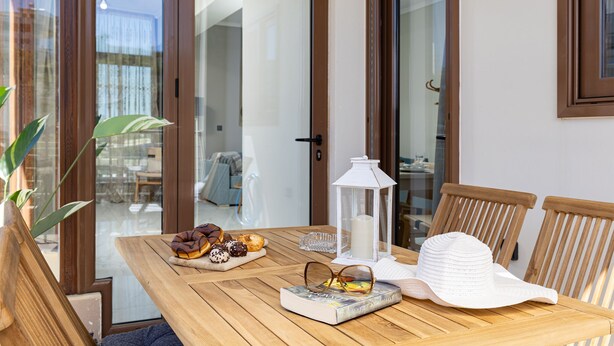 Une table en bois, une lanterne blanche, un chapeau blanc et un livre.