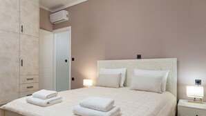 Un lit bien fait, avec deux serviettes pliées, une lampe de chevet et une table de nuit.