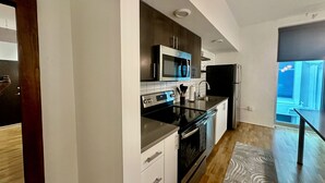 Una cocina moderna con electrodomésticos de acero inoxidable, armarios blancos y piso de madera.