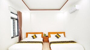 A hotel room with two wooden beds, white bedding, a nightstand, a window with curtains, and an air conditioning unit. - Moonlight Quynhon Hotel (Quy Nhon Nam)