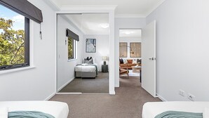 A modern hotel room with a large window, a bed, a desk, and a seating area with a sofa and a coffee table. - Luxury Perth Getaway: Modern Design (Perth WA)