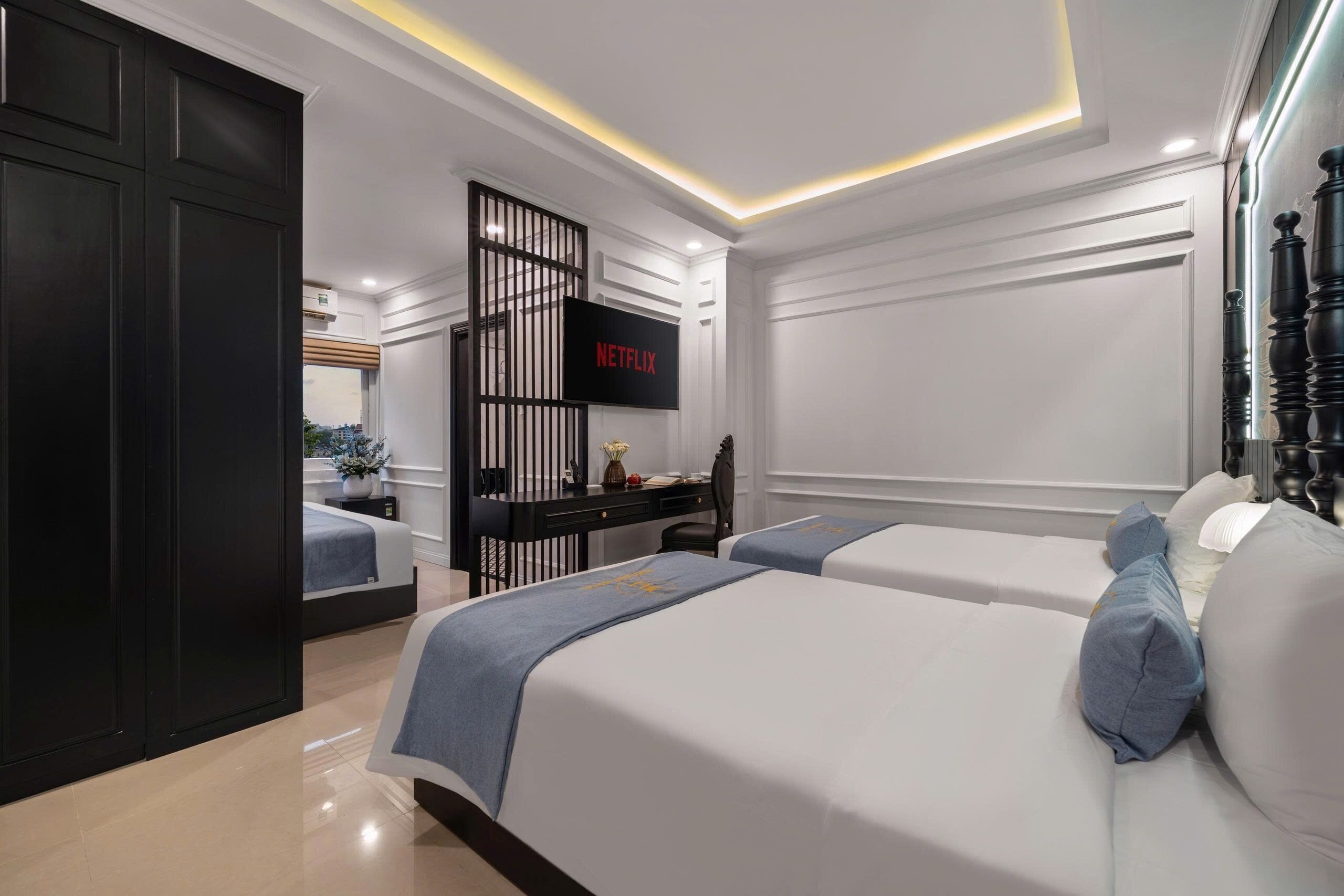 A modern hotel room with two beds, a TV, a desk, and a wardrobe.