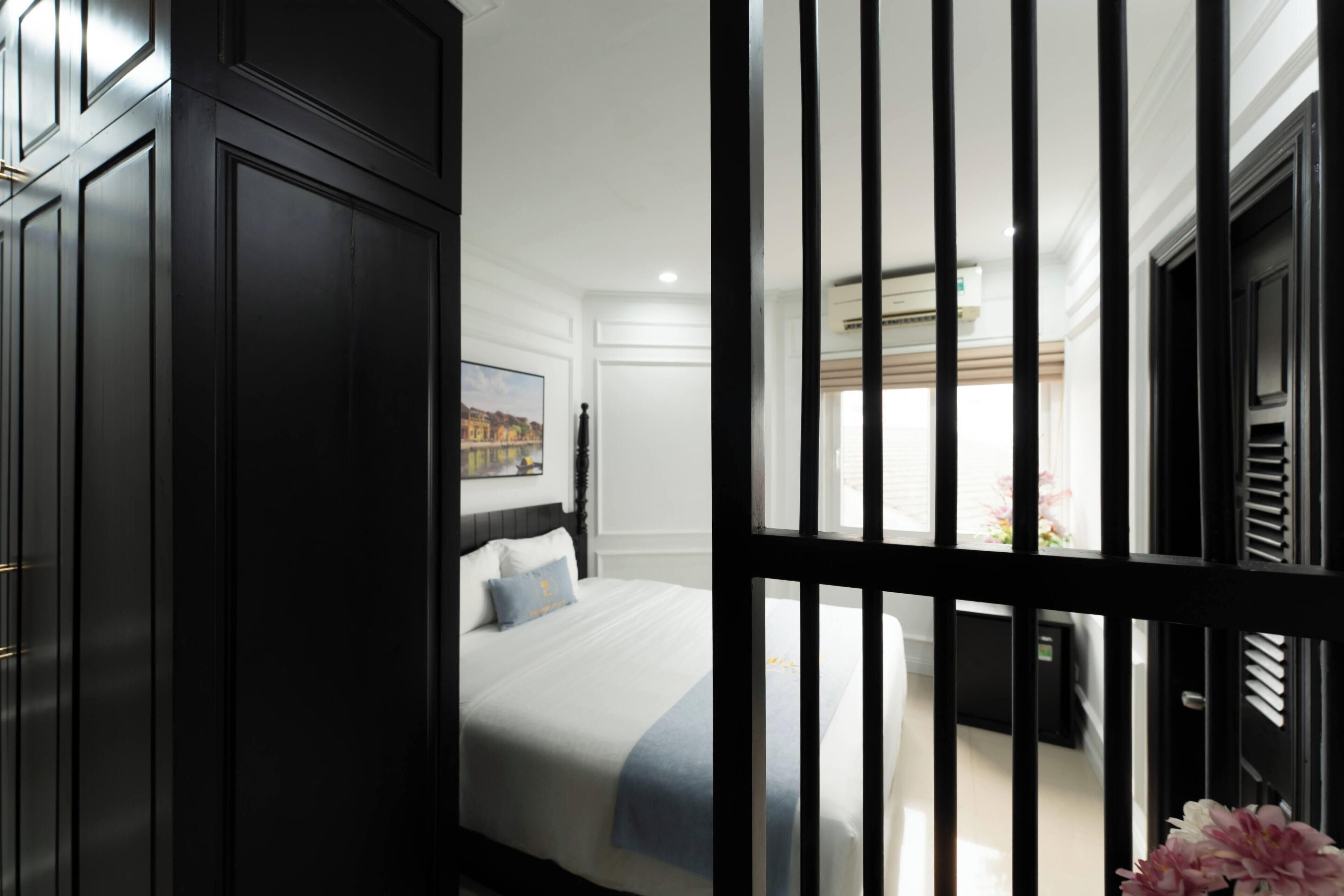 Un dormitorio con cama, mesita de noche, cómoda y ventana con vista al exterior.