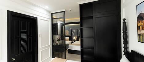 Un dormitorio con una cama, un armario negro, una puerta blanca y una estantería de pared.