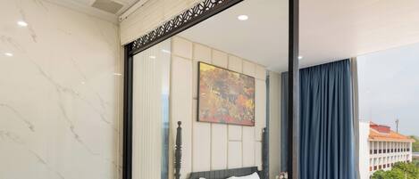 Habitación de hotel con una cama grande, una bañera, una mesita de noche con lámpara y un cuadro en la pared.