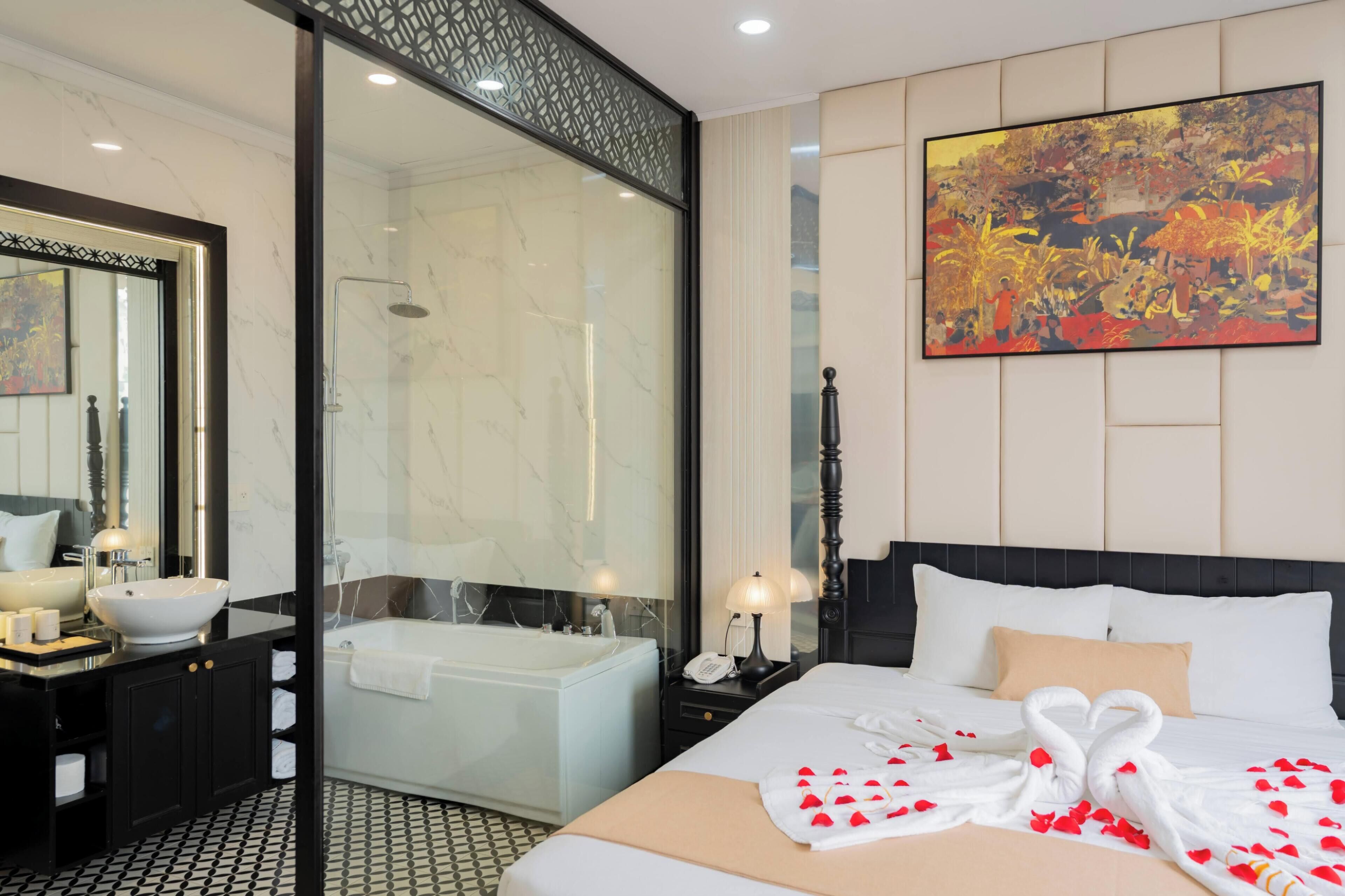A hotel room with a large bed, a bathtub, a glass shower enclosure, a painting on the wall, and a minibar.