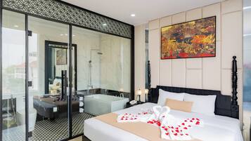 A hotel room with a large bed, a bathtub, a glass-enclosed shower area, and a large painting on the wall.