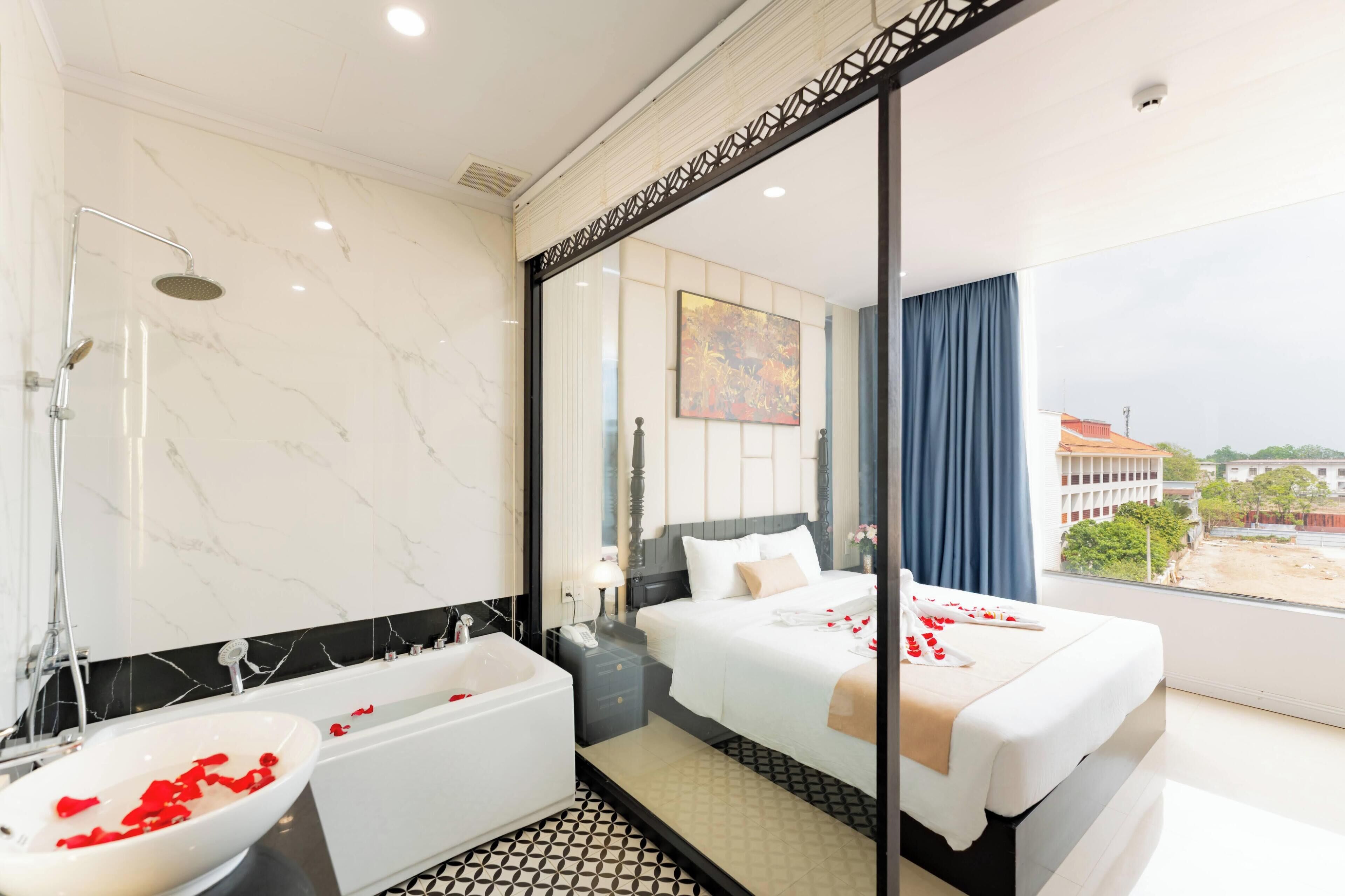 Habitación de hotel con una cama grande, una bañera y vistas a la ciudad.