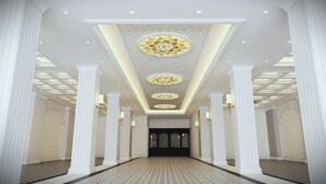 A hallway with a patterned floor, white columns, and a decorative ceiling with circular designs. - Elegant Hotel (Hue)