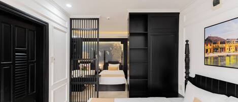 A bedroom with a bed, a black wardrobe, a black door, and a painting on the wall.