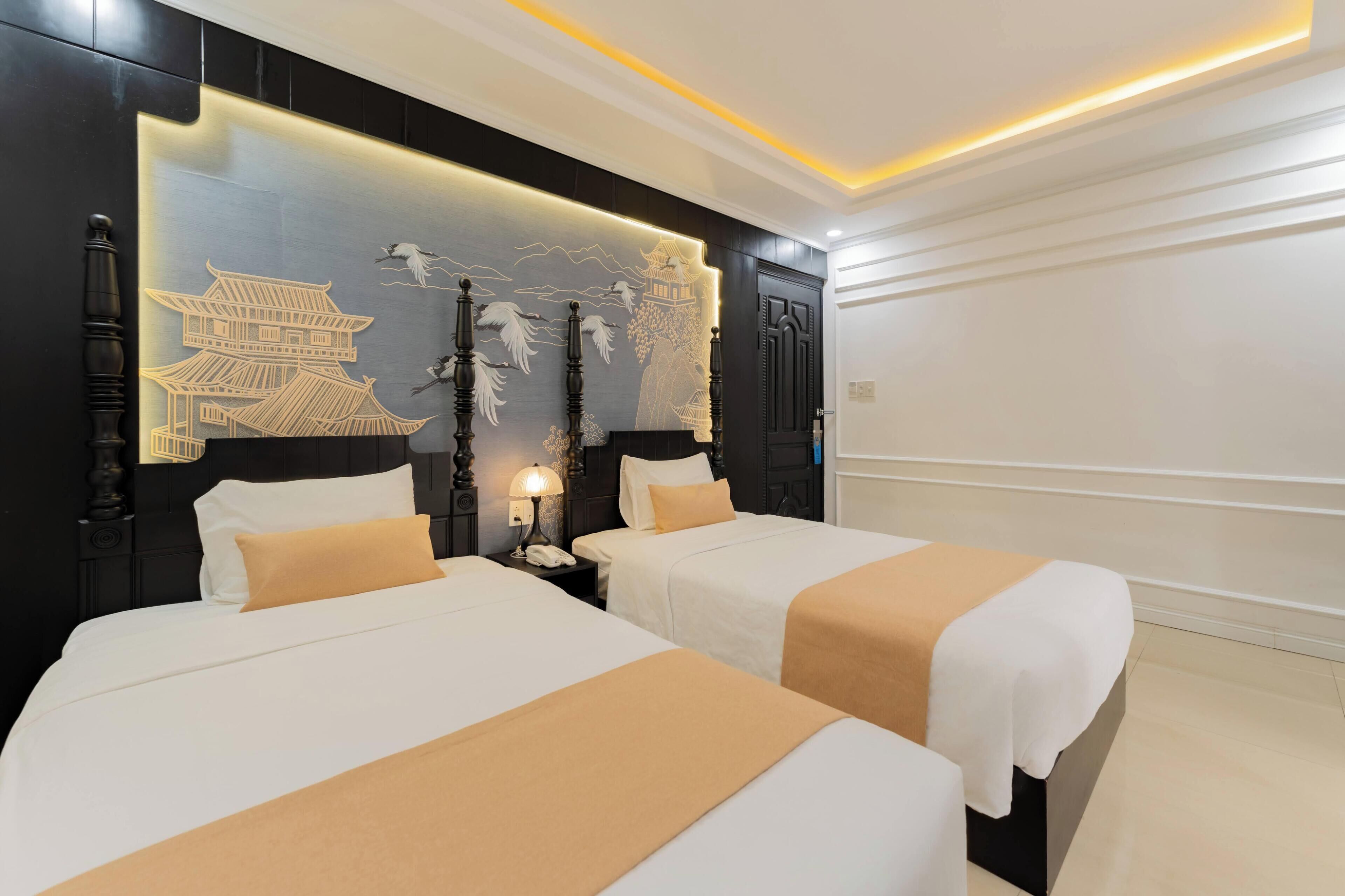 A hotel room with two beds, a decorative wall mural, and a nightstand with a lamp.