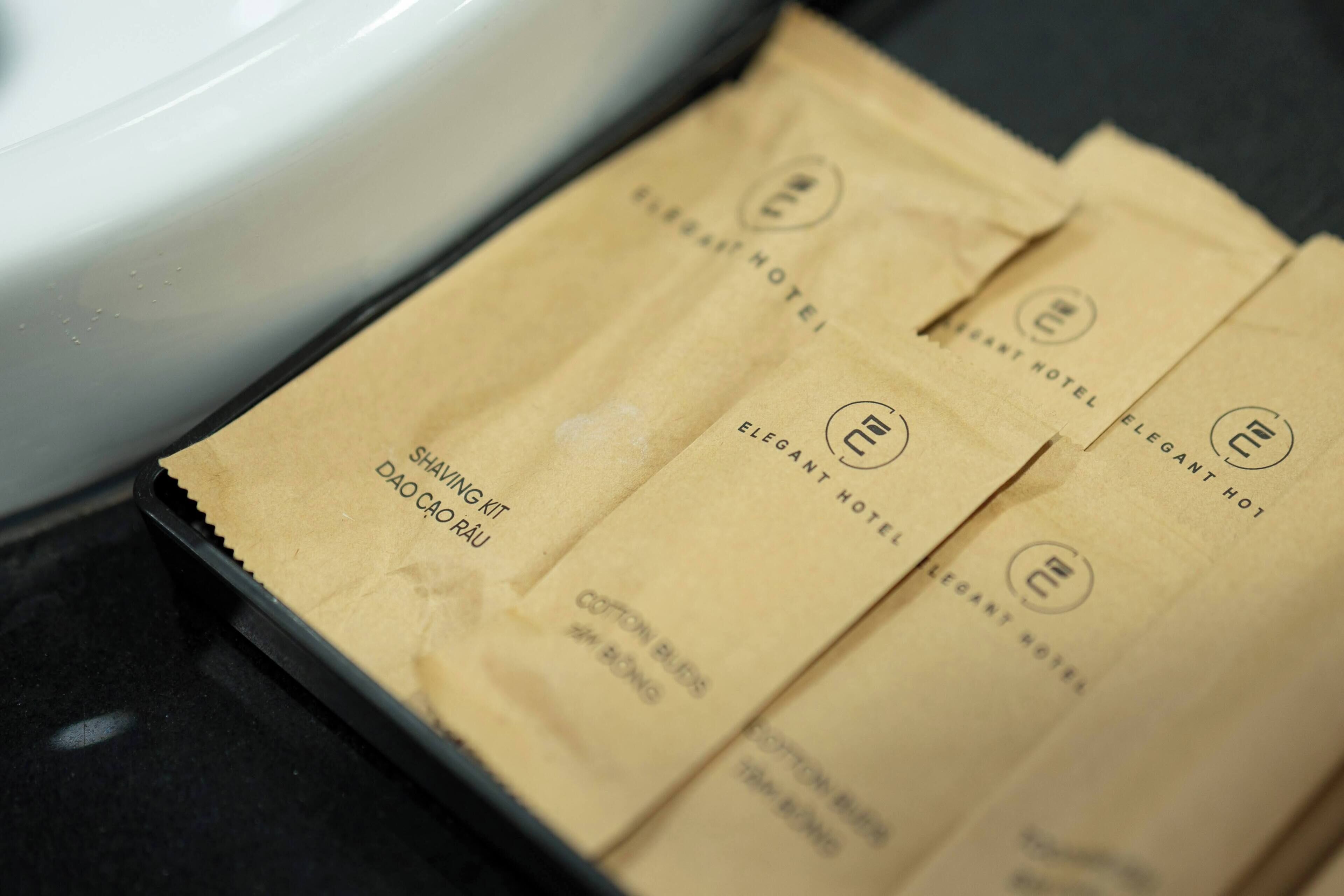 A set of brown paper bags with 'Elegant Hotel' branding, placed on a black surface.