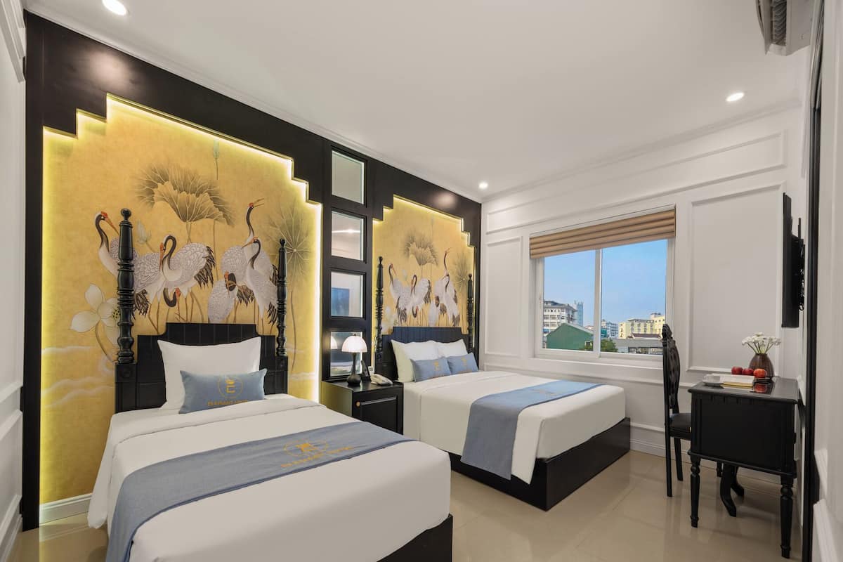 A hotel room with two beds, a desk, and a large window with a view.