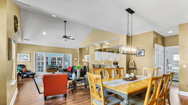 Un salón amplio con chimenea, un comedor con sillas y una mesa de madera, y una cocina al fondo.