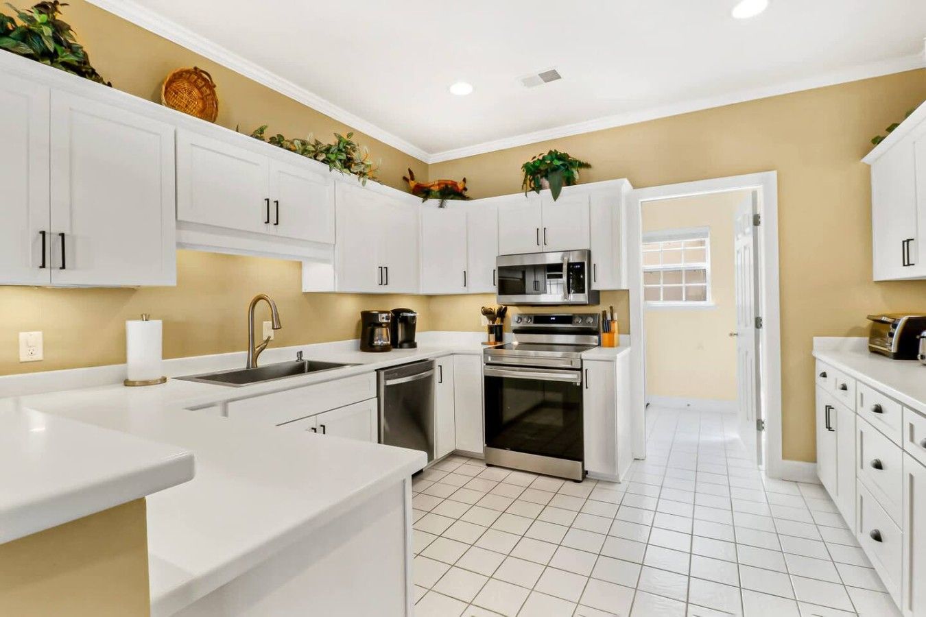A modern kitchen with white cabinetry, stainless steel appliances, and a tiled floor.