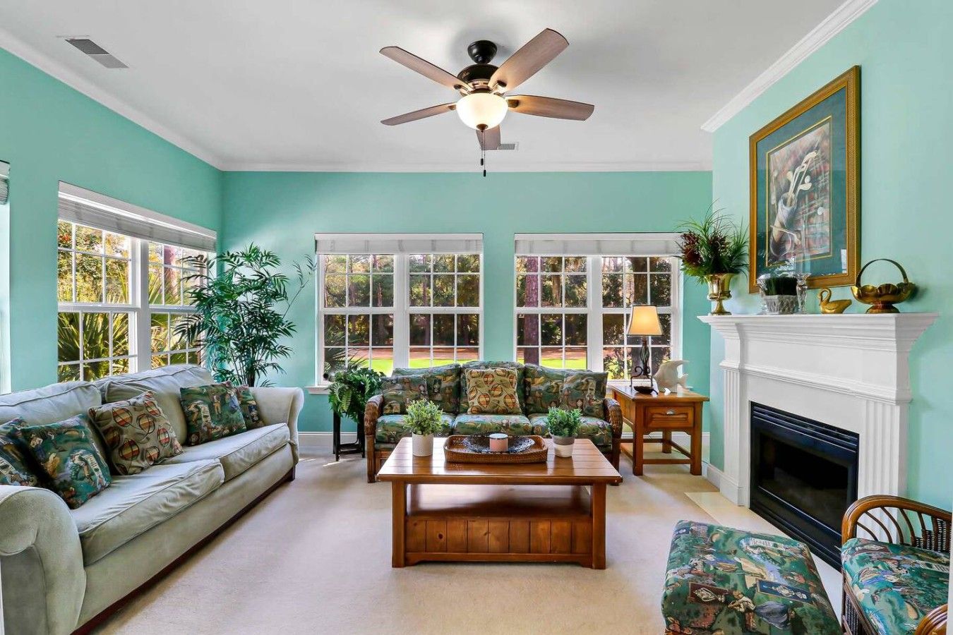 A living room with a sofa, armchair, coffee table, fireplace, and a ceiling fan.