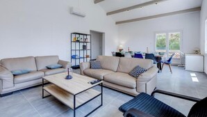 Ein modernes Wohnzimmer mit zwei beigefarbenen Sofas, einem Holztisch und einem Bücherregal.