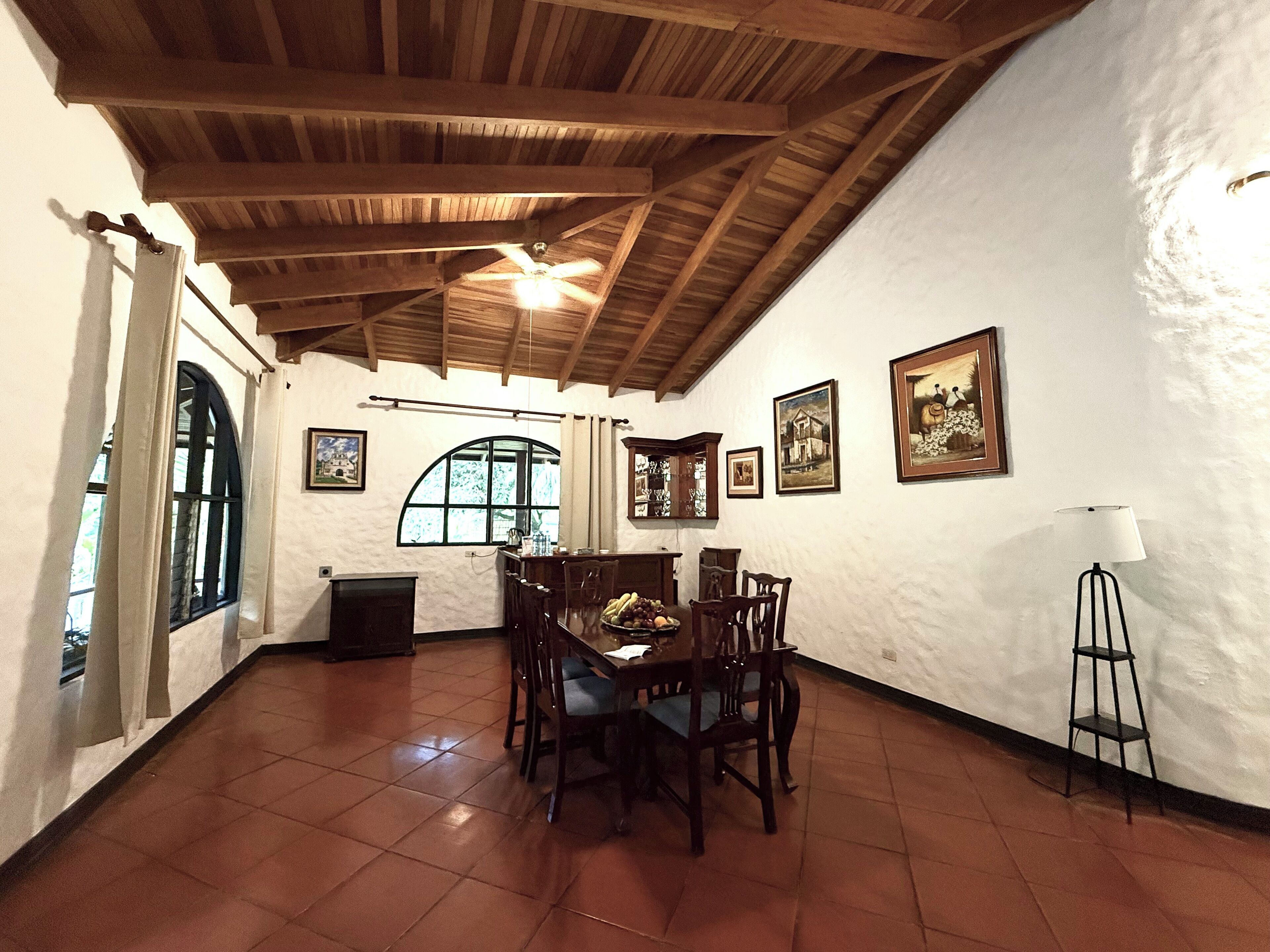 A dining area with a wooden ceiling, tiled floor, and a table set for four.
