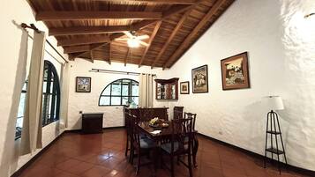 A dining area with a wooden ceiling, tiled floor, and a table set for four.