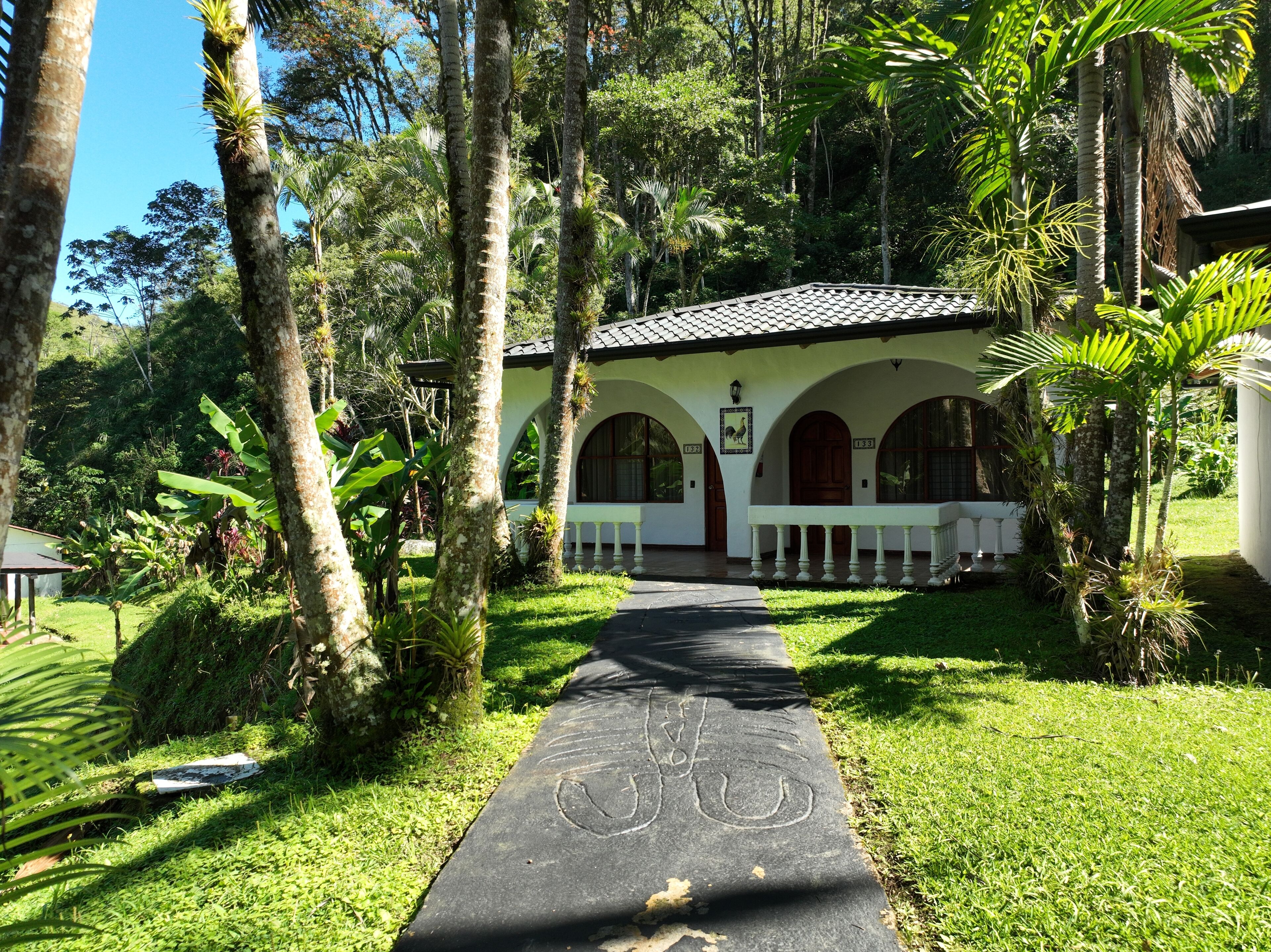 A building with a tiled roof, arched windows, and a pathway leading to it.