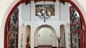 Ein gewölbter Gang mit Fliesenboden, einem Chandelier und einem Wandgemälde.