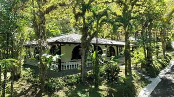 A traditional building with a tiled roof, surrounded by lush greenery and a white fence.