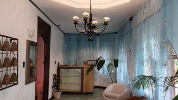 Une salle dotée d’un lustre, d’un comptoir d’accueil et d’espaces aménagés pour s’asseoir.