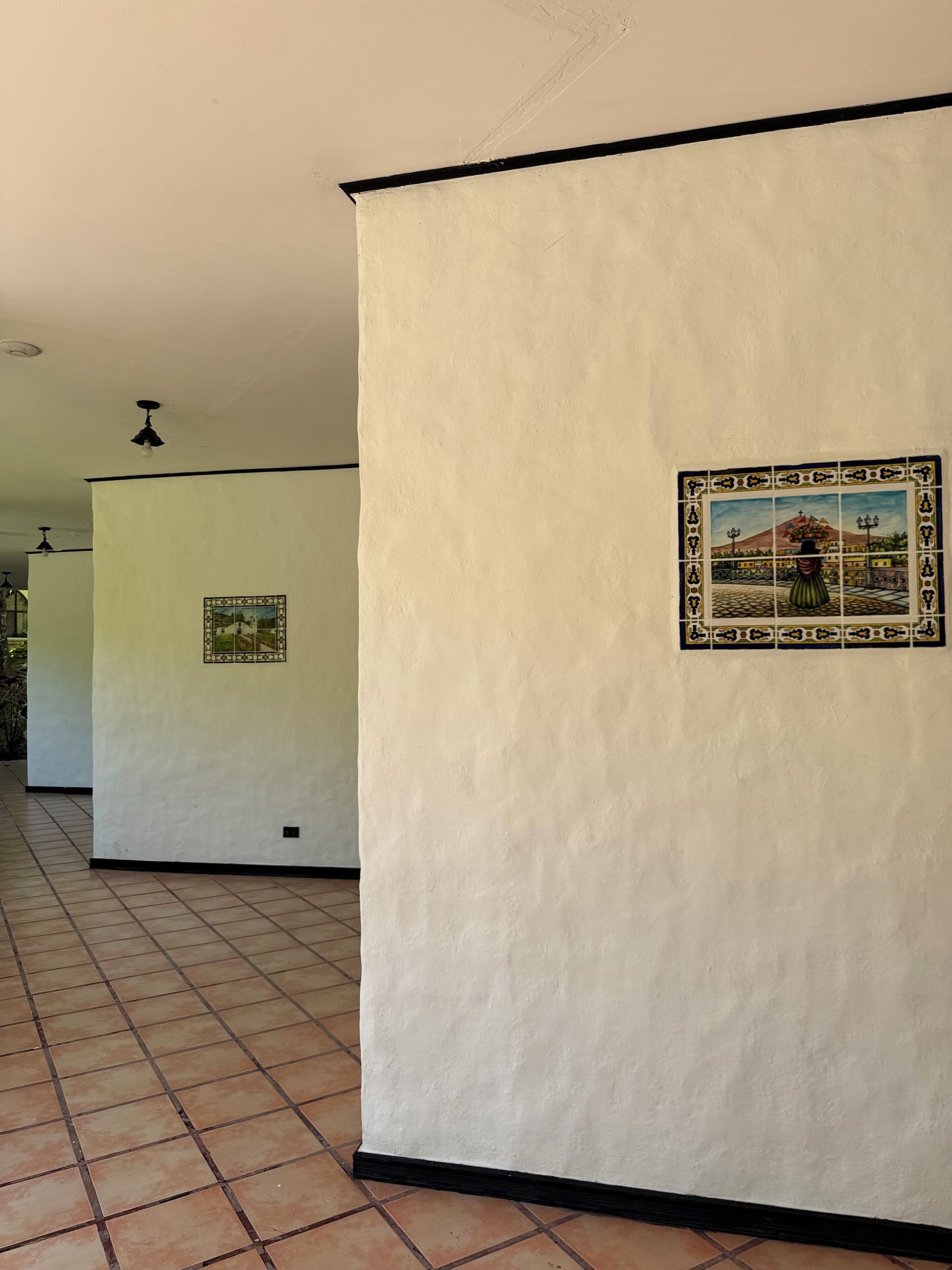Un pasillo con suelo de baldosas y paredes decoradas con cuadros enmarcados.