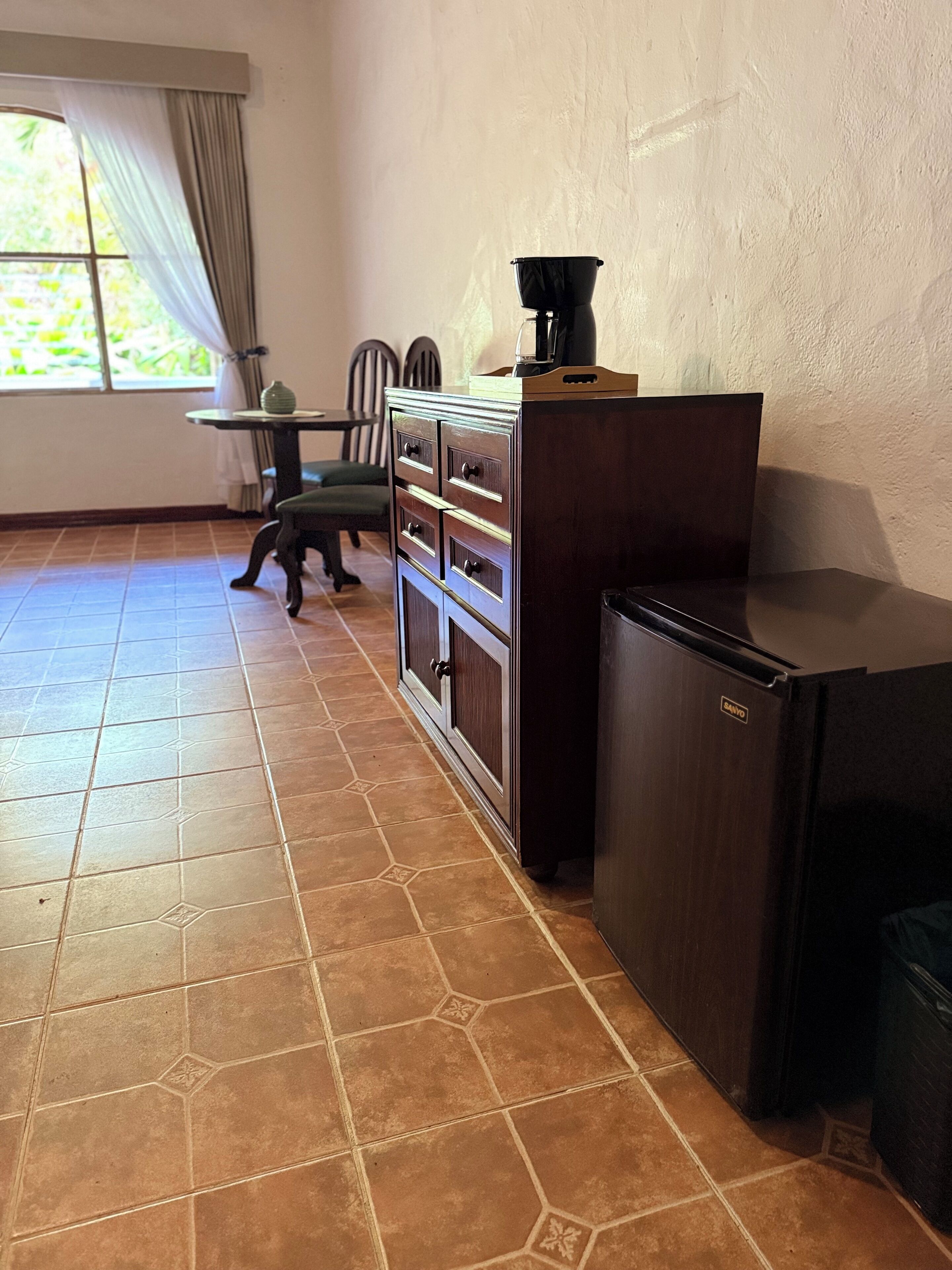 A kitchen with a refrigerator, a coffee maker, and a cabinet.