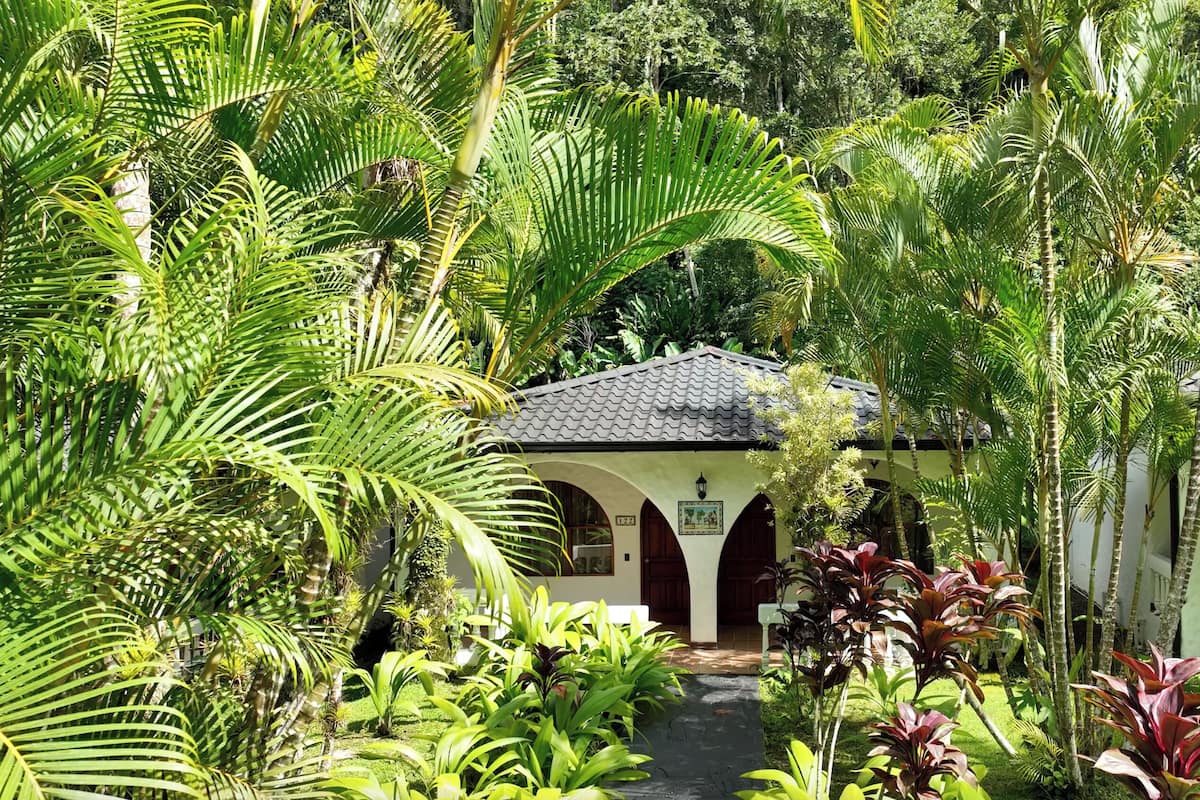 A traditional building with a tiled roof and arched entrance, surrounded by lush tropical vegetation.