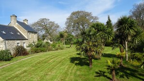 A stone house with a sloped roof and a well-maintained lawn.