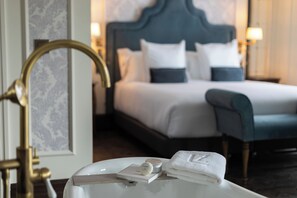 A hotel room with a bed, bedside lamps, a vanity with a mirror, and a towel. - Hotel Luze Boutique San Sebastián (San Sebastián)