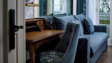 A cozy room with a wooden desk, a blue sofa, and a patterned chair.
