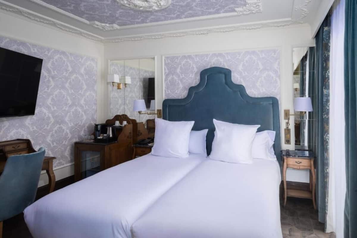 Una habitación de hotel con una cama grande, un escritorio, una silla, un televisor y un espejo.