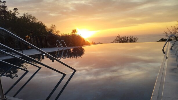 Una piscina a sfioro con vista sul tramonto sull'acqua.