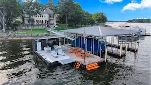 A docked boat with outdoor seating and a covered area, surrounded by water and trees.