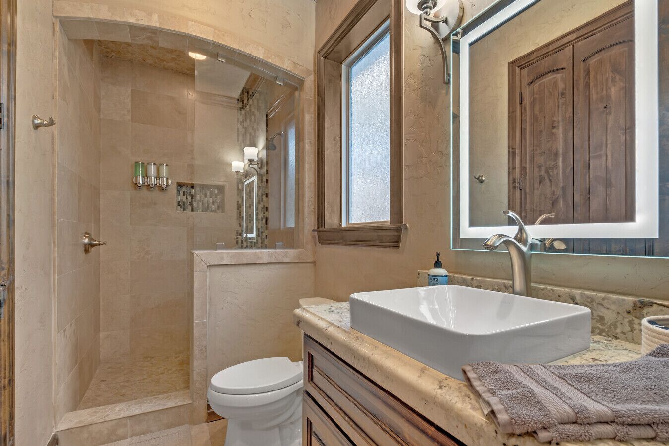 Une salle de bain avec une douche à l’italienne, des toilettes, un lavabo et un grand miroir.