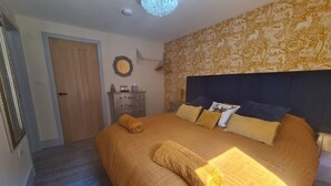 Une chambre à coucher avec un grand lit, une commode, une porte et un mur décoré d’un motif.