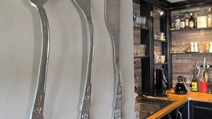 Een keuken met een zwart aanrecht, een spoelbak en een achterwand met een houtstructuur.