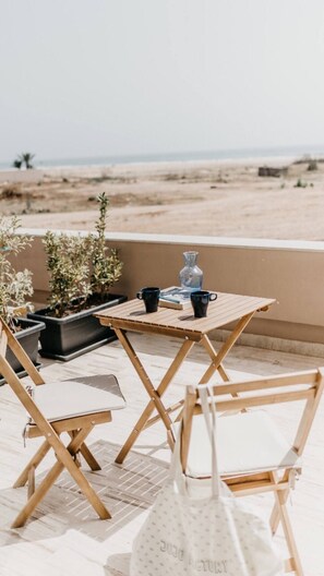 Relax in a tranquil beachside setting with a table for two and a serene ocean view.