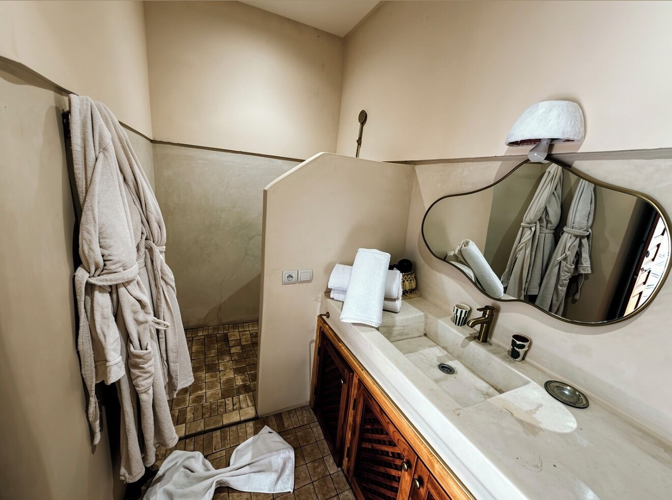 A bathroom with a vanity, a mirror, a towel rack, and a shower area.
