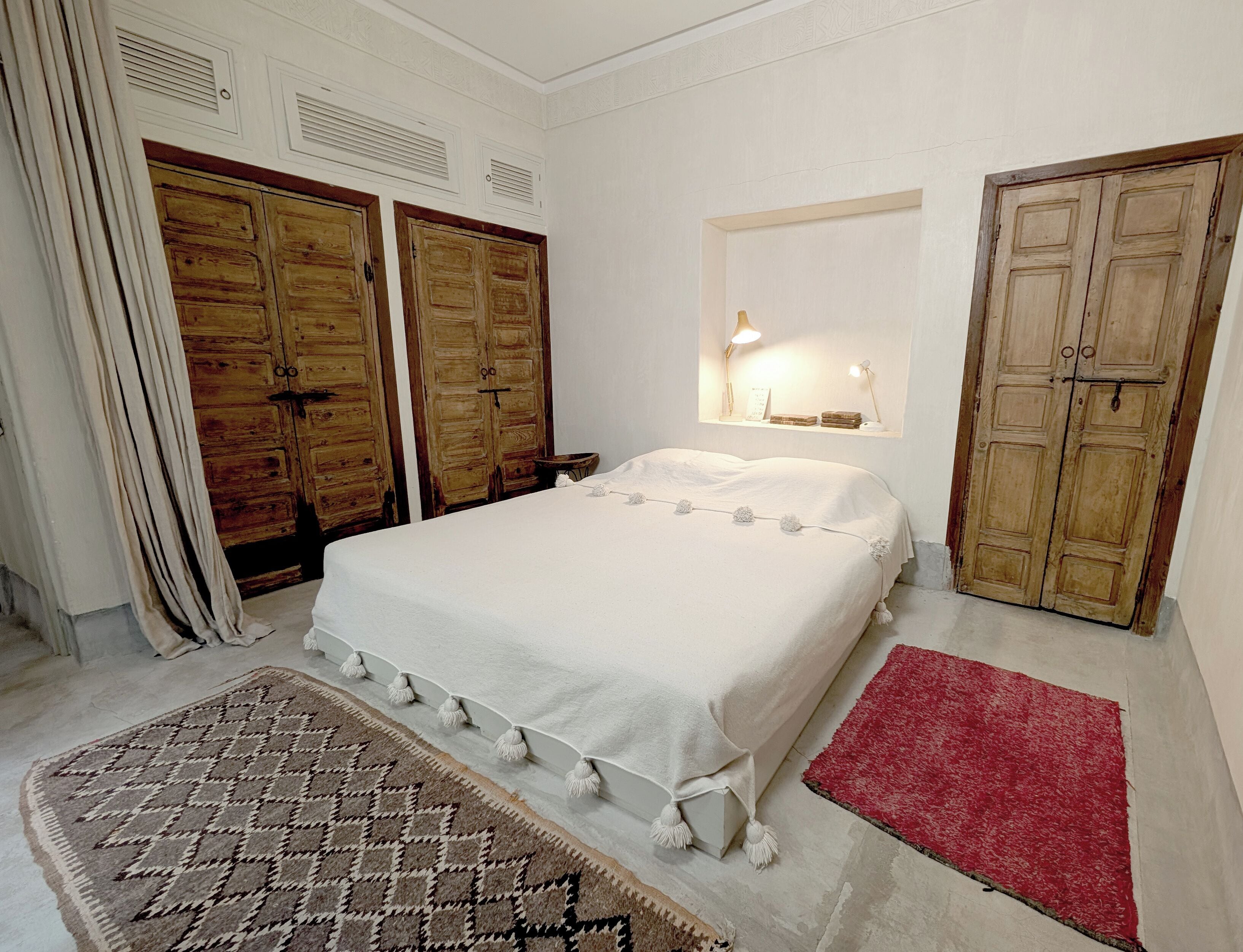 Ein Schlafzimmer mit einem großen Bett, Holzschränken, einem roten Teppich und einem gemusterten Teppich.
