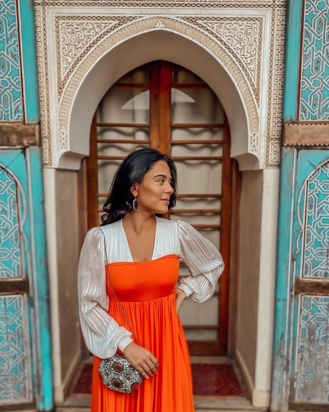 A person standing in front of an intricately designed doorway with geometric patterns.