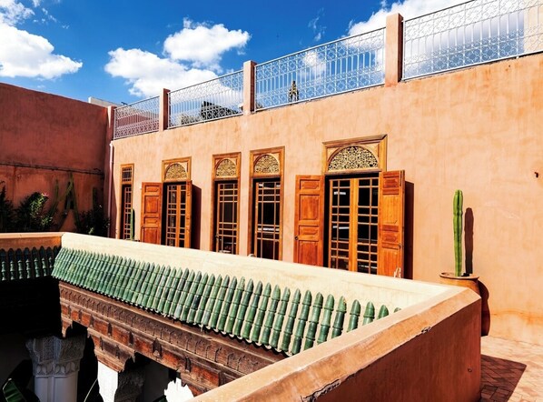 Ein Innenhof mit einem langen, schmalen Pool, einem Kaktus und einem Gebäude mit Holztüren und -fenstern.