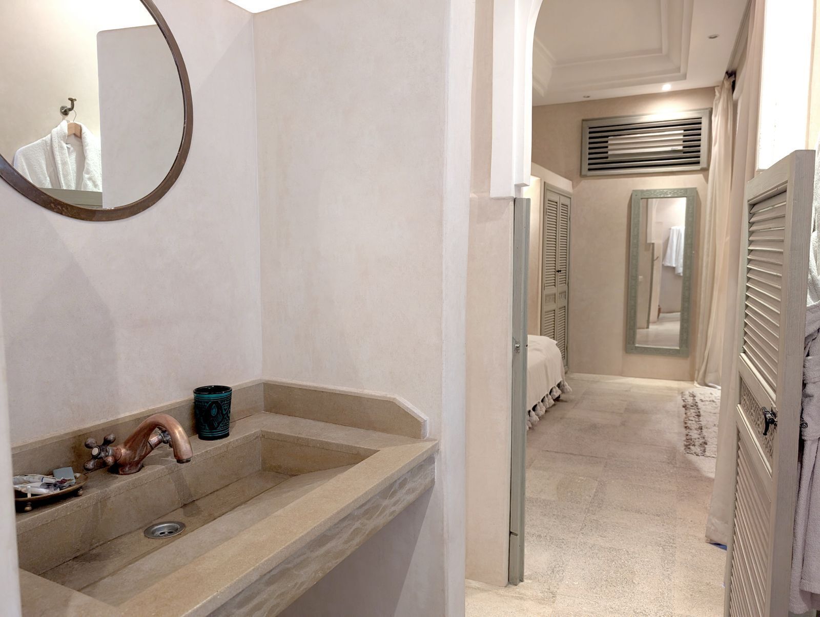 Un baño con un lavamanos color crema, un espejo y un perchero para toallas.
