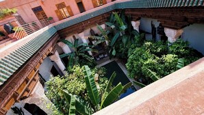 Une cour avec une piscine, entourée de bâtiments à l’architecture traditionnelle et d’un pont en bois.