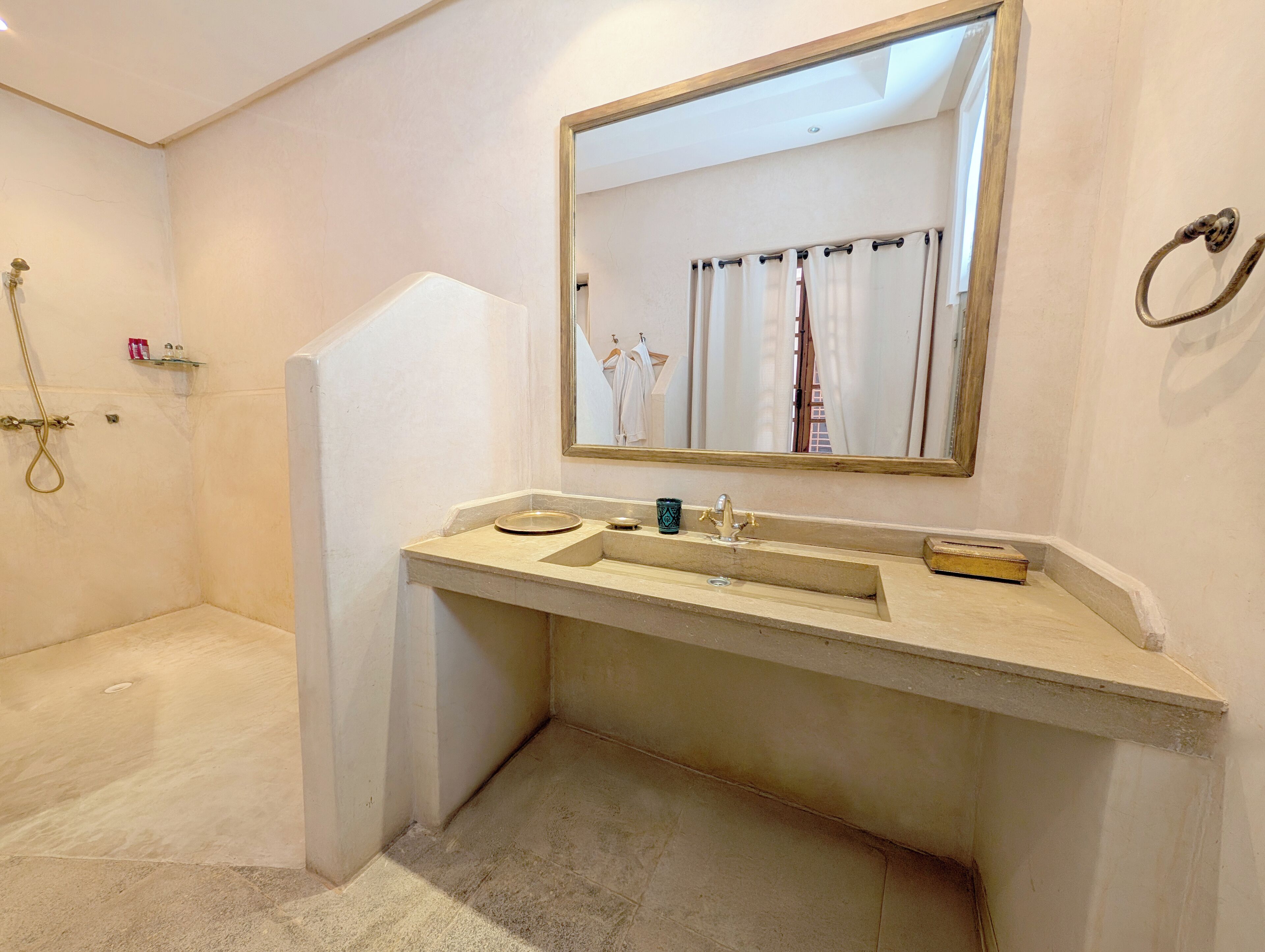 Une salle de bain équipée d’un lavabo, d’un miroir, d’une douche et d’un porte-serviettes.