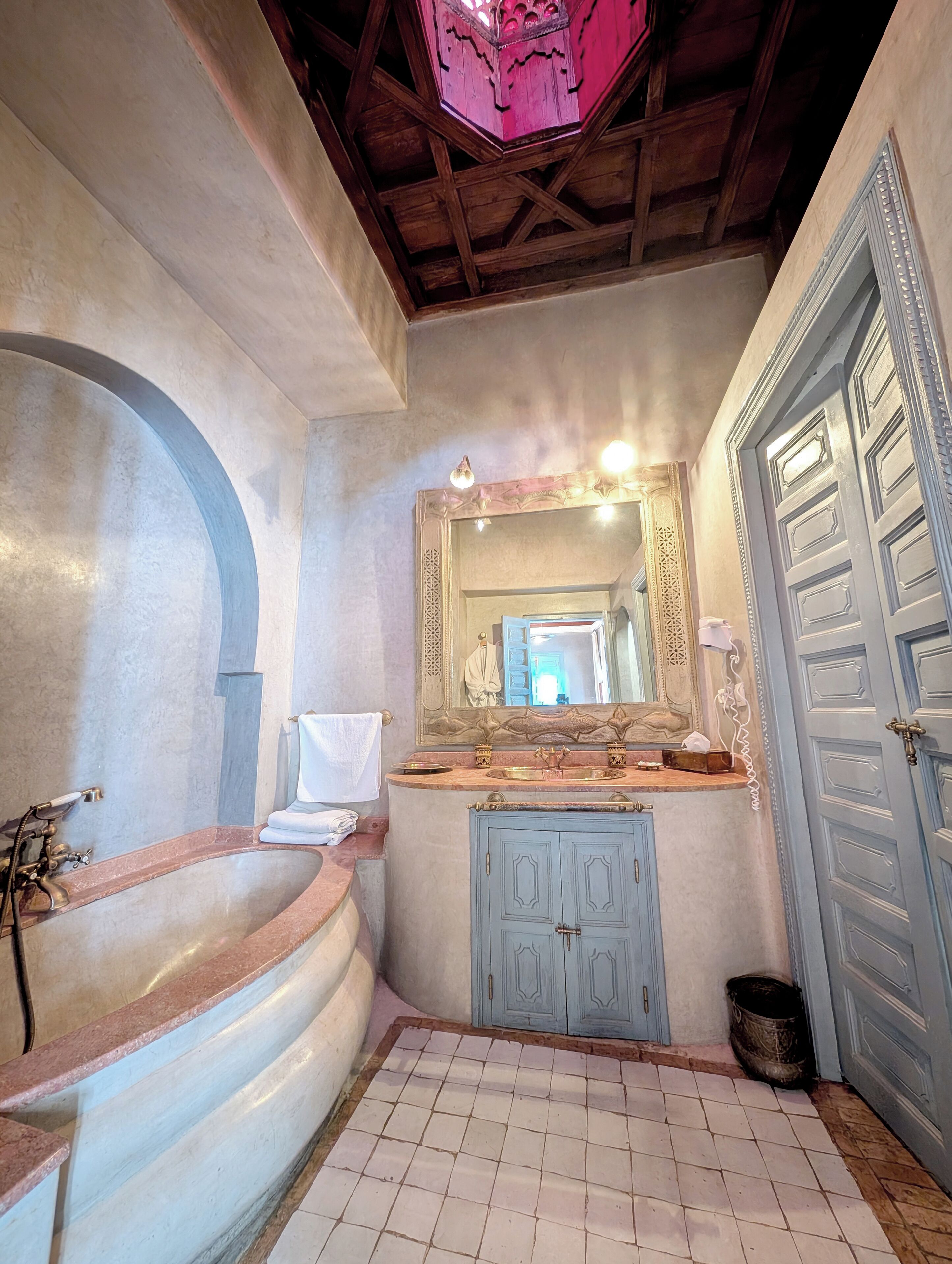 Une salle de bain avec un lavabo en marbre, un grand miroir et un meuble bleu.